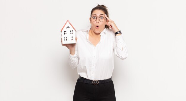 Young blonde woman looking surprised, open-mouthed, shocked, realizing a new thought, idea or concept