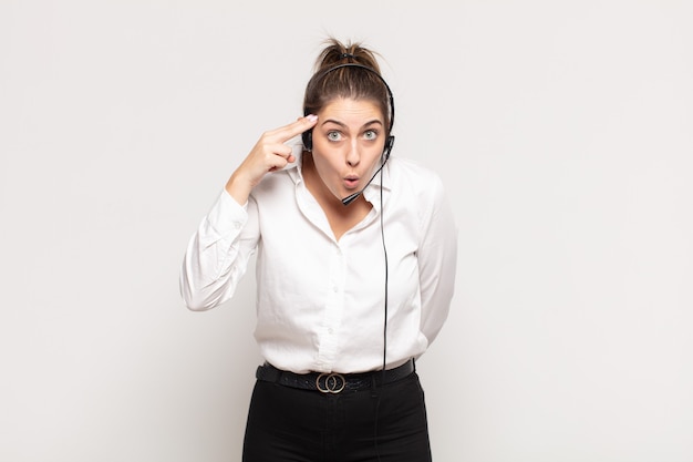 Young blonde woman looking surprised, open-mouthed, shocked, realizing a new thought, idea or concept