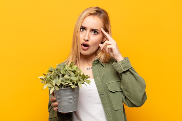 Young blonde woman looking surprised, open-mouthed, shocked, realizing a new thought, idea or concept