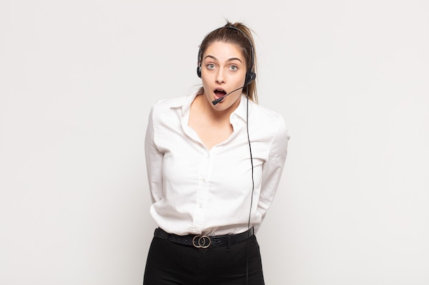 Young blonde woman looking very shocked or surprised, staring with open mouth saying wow