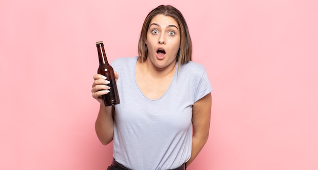 Young blonde woman looking very shocked or surprised, staring with open mouth saying wow