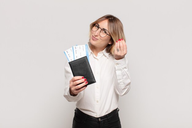 Young blonde woman making capice or money gesture, telling you to pay your debts!