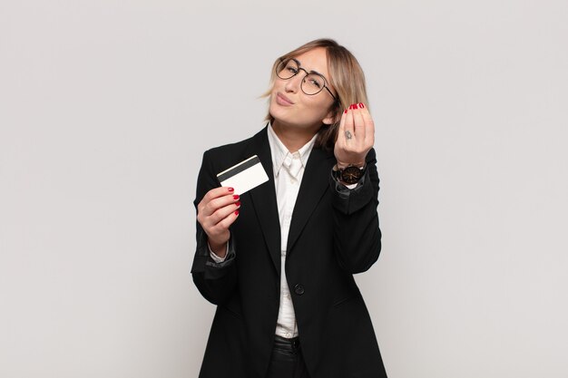 Young blonde woman making capice or money gesture