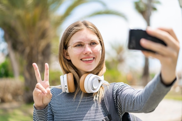 Young blonde woman at outdoors doing a selfie