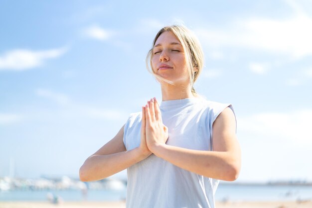 Young blonde woman at outdoors doing yoga