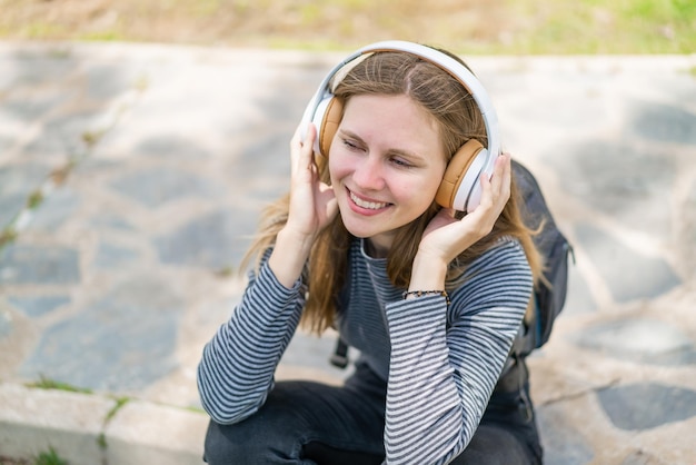 Молодая блондинка на открытом воздухе слушает музыку