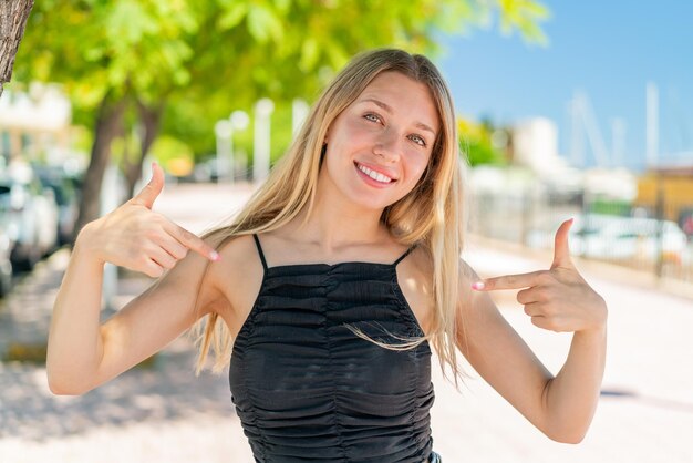 Foto giovane donna bionda all'aria aperta orgogliosa e soddisfatta