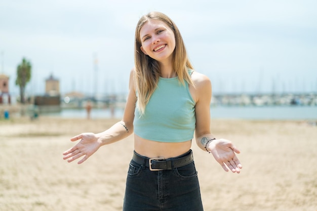 Young blonde woman at outdoors smiling