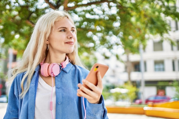 晴れた日に屋外でスマートフォンを使用して若いブロンドの女性