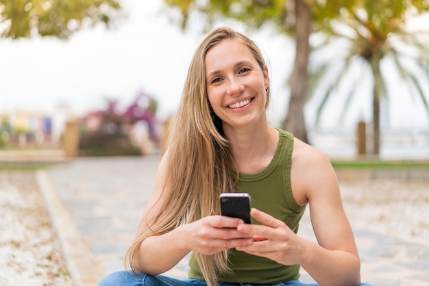 Young blonde woman at outdoors using mobile phone