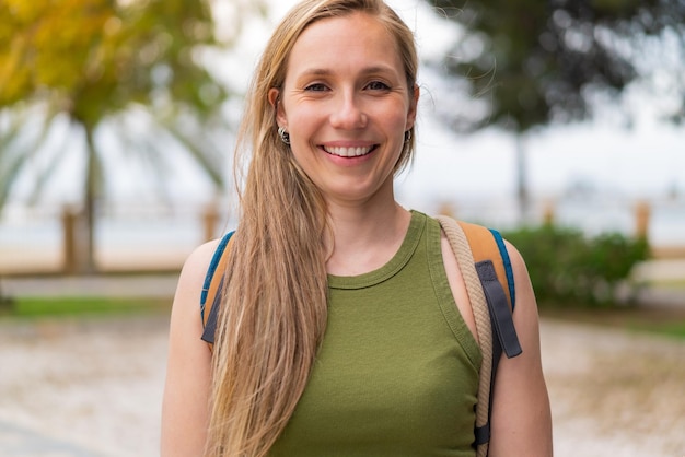 Young blonde woman at outdoors with happy expression