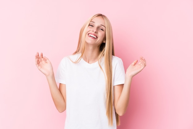 Young blonde woman on pink background joyful laughing a lot.