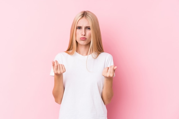 Young blonde woman on pink wall showing that she has no money.