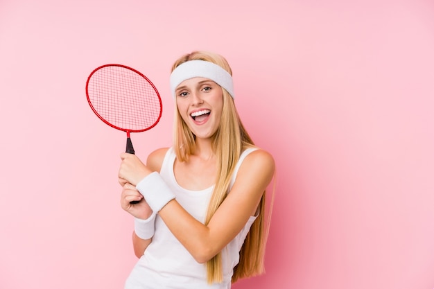 Young blonde woman playing badminton isolated