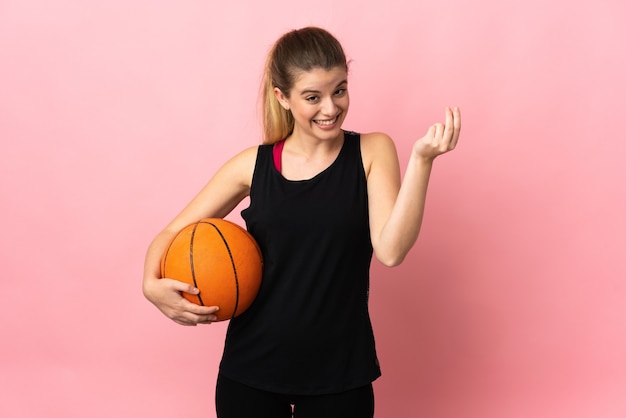 Young blonde woman playing basketball posing isolated against the blank wall