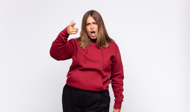 Young blonde woman pointing at camera with an angry aggressive expression looking like a furious, crazy boss