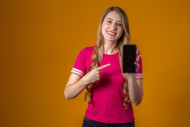 Young blonde woman pointing to cell phone.