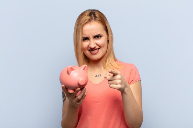 Young blonde woman pointing forward at camera with both fingers and angry expression, telling you to do your duty