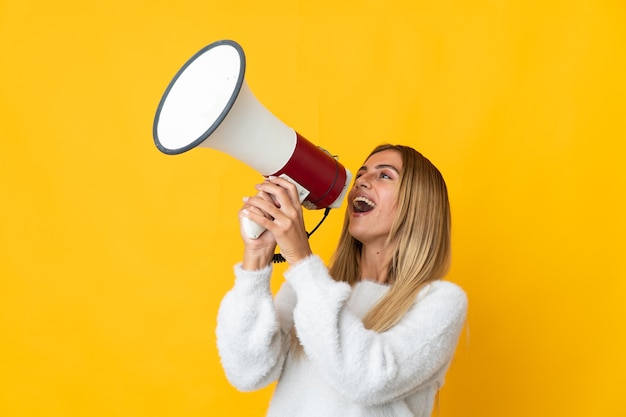 Young blonde woman posing isolated against the blank wall