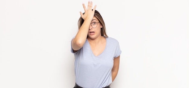 Young blonde woman raising palm to forehead thinking oops, after making a stupid mistake or remembering, feeling dumb