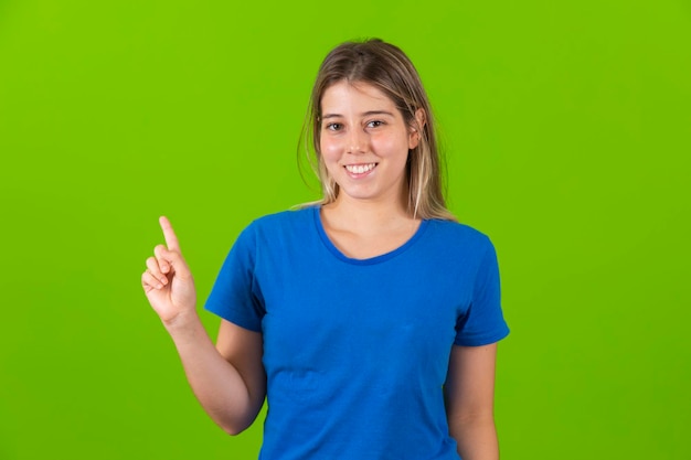 Young blonde woman showing free space for text on green background