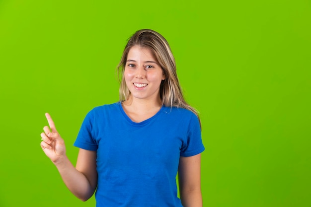 Young blonde woman showing free space for text on green background