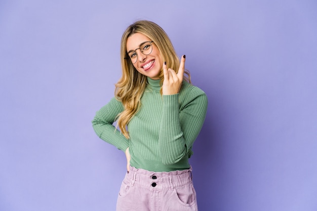 Young blonde woman showing rock gesture with fingers