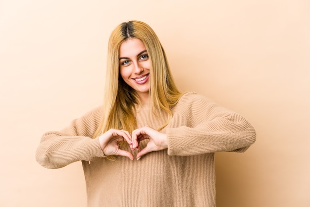 Фото Молодая блондинка женщина улыбается и показывает форму сердца руками