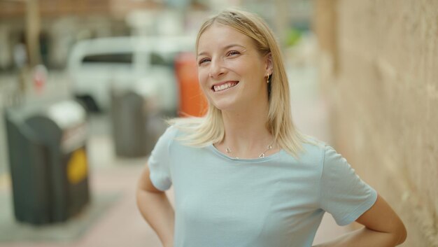 自信を持って通りに立っている笑顔の若いブロンドの女性