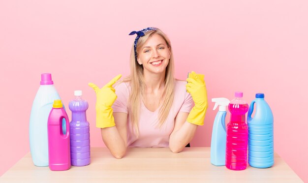 Young blonde woman smiling confidently pointing to own broad smile. housekeeper concept