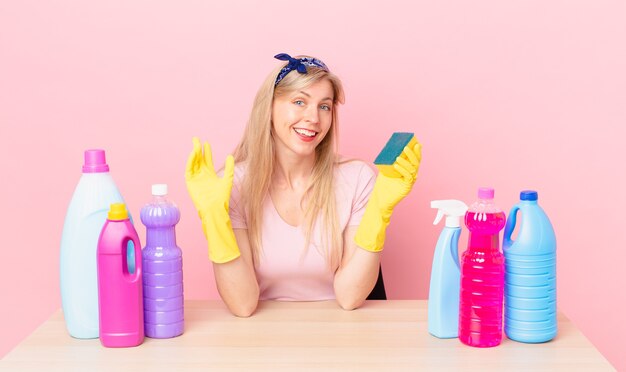 幸せに笑って、手を振って、あなたを歓迎し、挨拶する若いブロンドの女性。ハウスキーパーのコンセプト