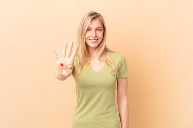 Young blonde woman smiling and looking friendly, showing number four