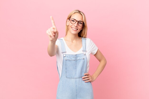 Young blonde woman smiling and looking friendly, showing number one