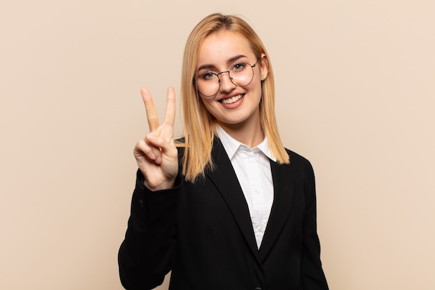 Young blonde woman smiling and looking friendly, showing number two or second with hand forward, counting down