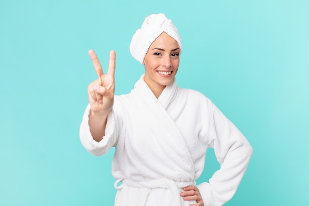 Young blonde woman smiling and looking friendly, showing number two. shower concept.