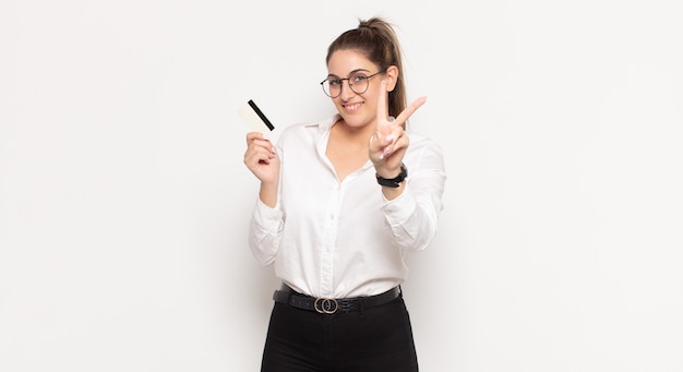 Young blonde woman smiling and looking happy, carefree and positive, gesturing victory or peace with one hand