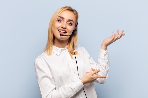 Young blonde woman smiling proudly and confidently, feeling happy and satisfied and showing a concept on copy space