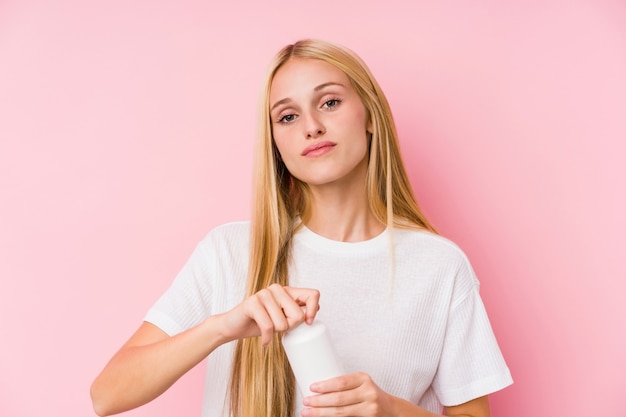 Giovane donna bionda che prende alcune pillole isolate su un blackground