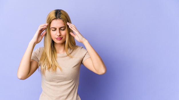 Young blonde woman touching temples and having headache