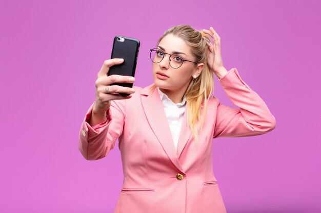 彼女のスマートフォンを使用して若いブロンドの女性