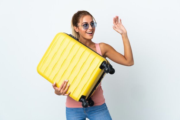 Молодая блондинка в отпуске с дорожным чемоданом и салютом