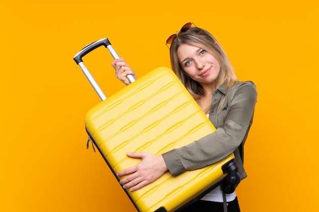 Giovane donna bionda in vacanza con la valigia di viaggio