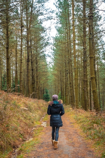 young blonde woman walking through a beautiful pine forest