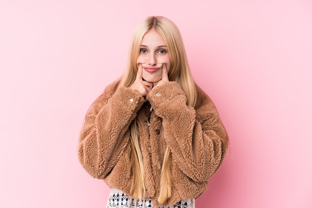 Young blonde woman wearing a coat doubting between two options