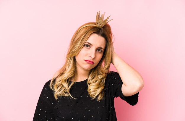 Young blonde woman wearing a crown isolated being shocked, she has remembered important meeting.