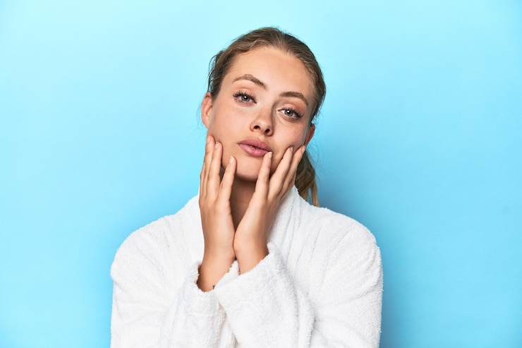 Photo young blonde woman in a white robe posing seriously in a studio
