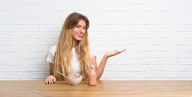 Giovane donna bionda con una ciotola di cereali in mano qualcosa