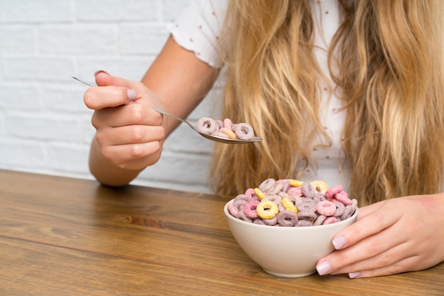 Giovane donna bionda con ciotola di cereali