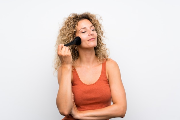 Young blonde woman with curly hair with makeup brush