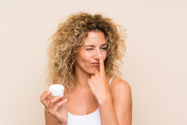 Young blonde woman with curly hair with moisturizer